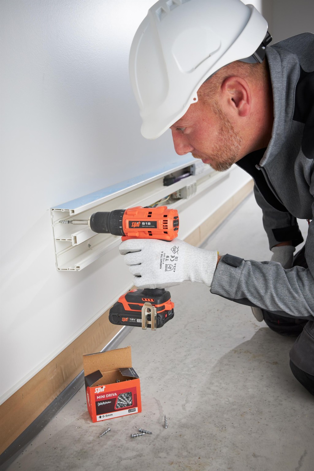 An orange and black Spit cordless power tool, with an ergonomic grip, designed for use on construction and maintenance tasks.