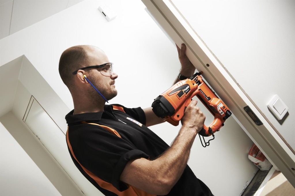 A Paslode cordless stapler with a magazine feed and safety tip, for fastening materials using heavy-duty staples.