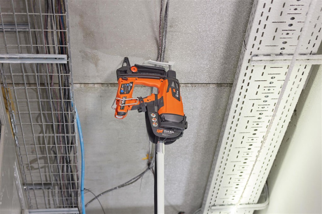 An orange and black Spit cordless power tool, with an ergonomic grip, designed for use on construction and maintenance tasks.