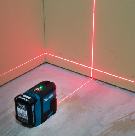 A teal and black Makita self-levelling laser level projecting horizontal and vertical lines, for precision alignment and setting-out work.