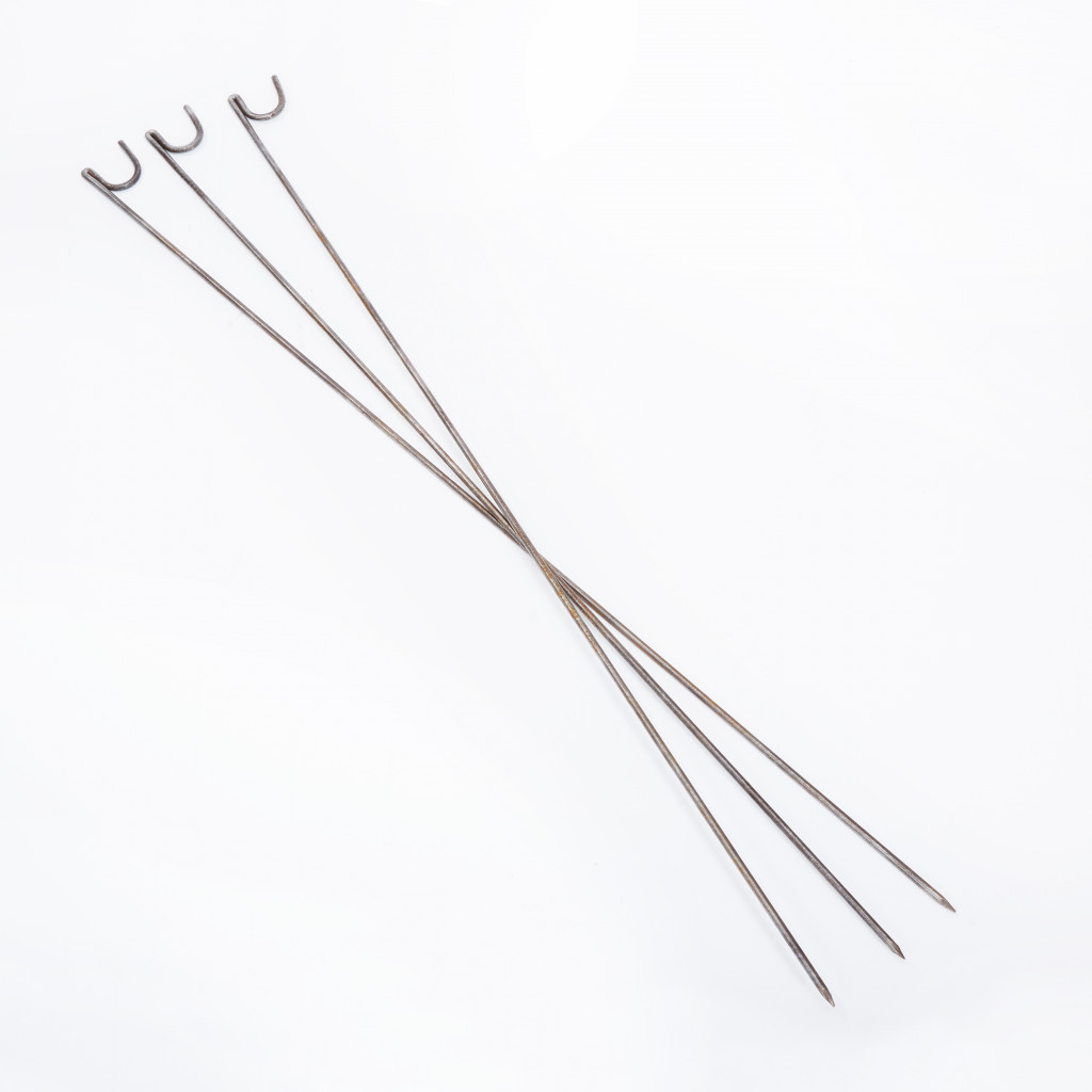 Four long, metal skewers with hooked ends are arranged in an overlapping X pattern on a white background.
