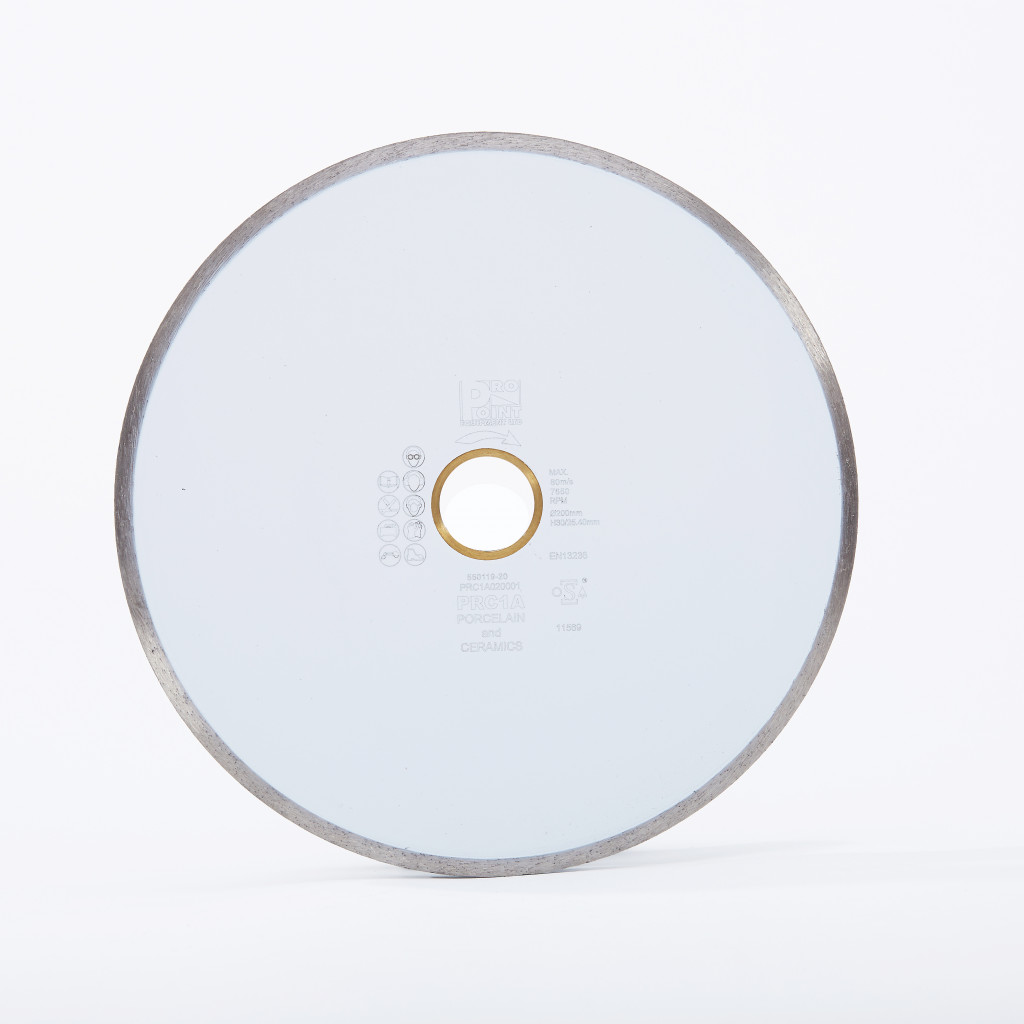 A round ceramic cutting blade with a metallic edge and a central hole, displayed upright against a plain white background. Text and small symbols are printed in the center of the blade.