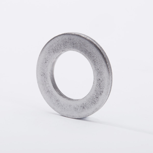 A metallic washer standing upright on a white surface, with a circular hole in the center and a slightly textured, silver-gray finish.