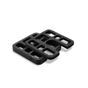 Two black rectangular plastic shims with slots and cutouts, stacked slightly askew on a white background.