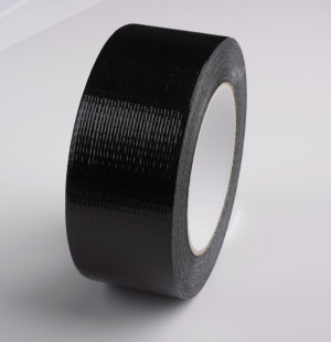 A single roll of black duct tape is standing upright on a smooth, white surface, showing its textured, glossy finish and the cardboard core in the center.