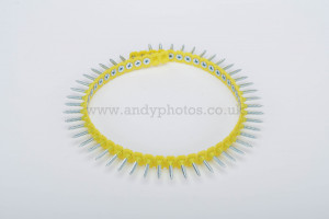 A yellow plastic strip forms a circle, holding evenly spaced silver screws pointing outward, resembling a crown or gear, on a plain white background.
