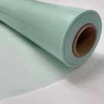 A close-up of a large roll of light green plastic or vinyl sheet material, partially unrolled on a white surface.