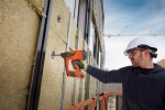 An orange and black Spit cordless power tool, with an ergonomic grip, designed for use on construction and maintenance tasks.