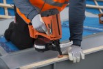 An orange and black Paslode cordless brad nailer with an angled magazine, designed for driving fine brad nails in trim and finish carpentry.