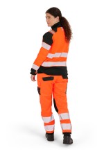 A women's high-visibility orange jacket featuring retroreflective tape panels, suitable for a wide range of outdoor and site work applications.