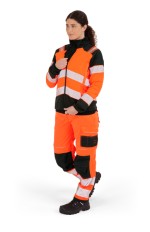A women's high-visibility orange jacket featuring retroreflective tape panels, suitable for a wide range of outdoor and site work applications.