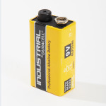 A yellow Duracell Industrial 9V professional alkaline battery standing upright on a white background. The branding and specifications are visible on the batterys label.,