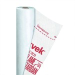 A roll of white building wrap partially unrolled, revealing red printed text and symbols, including a dotted line labeled Überlappung and Overlap on the sheet.