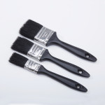Three black-handled paintbrushes of varying sizes are arranged parallel on a white background, with their bristles facing left. Each brush has a hole at the end of the handle for hanging.