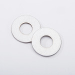 Two flat, round metal washers with central holes are lying on a white background, slightly overlapping each other.