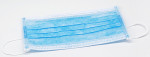 A blue disposable surgical face mask with white ear loops, lying flat on a white surface.