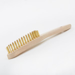 A wire brush with steel or brass bristle rows in a wooden or plastic handle, for removing rust, scale, and surface contaminants from metal.