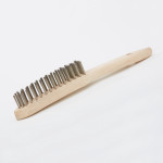 A wire brush with steel or brass bristle rows in a wooden or plastic handle, for removing rust, scale, and surface contaminants from metal.