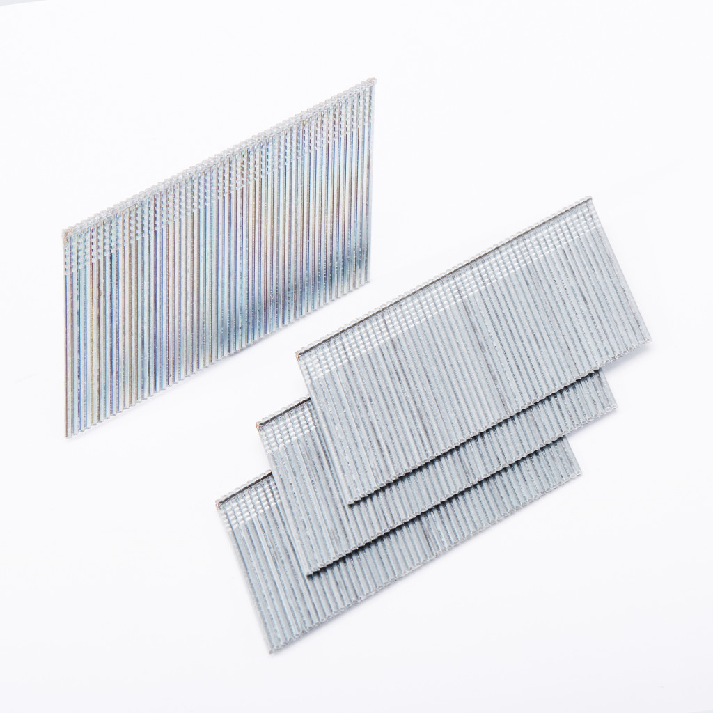Four strips of metal nails or staples are arranged on a white surface, with three overlapping in the foreground and one standing upright in the background.