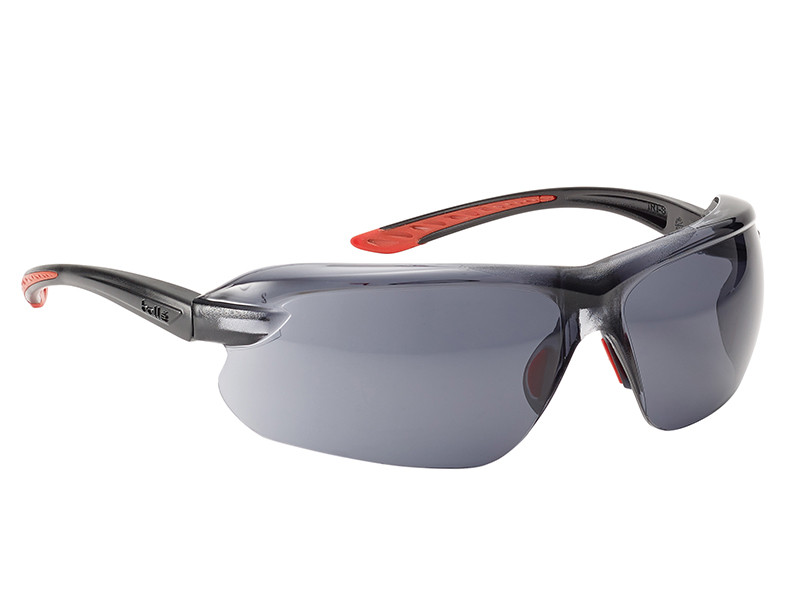 A pair of sleek, wraparound safety glasses with dark tinted lenses, black frames, and red accents on the arms.