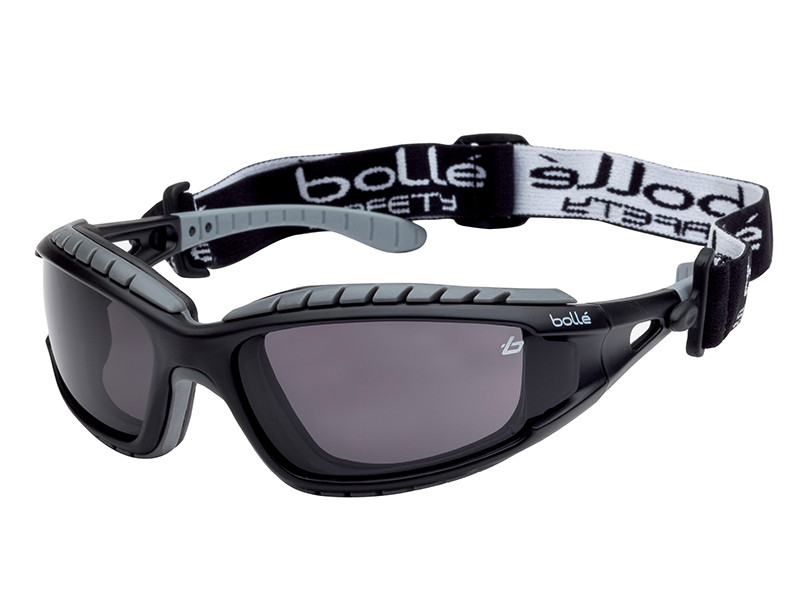 Black and gray safety goggles with dark lenses, featuring a wraparound design and an adjustable elastic strap displaying the “Bollé Safety” logo in white text.