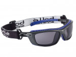 A pair of black and blue safety goggles with tinted lenses, a thick adjustable elastic strap, and side ventilation. The strap features the brand name Bollé Safety in white letters.