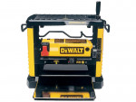 A yellow and black DeWalt wood planer with a metal base, front and top handles, and adjustment knobs, designed for smoothing or thinning wood boards.