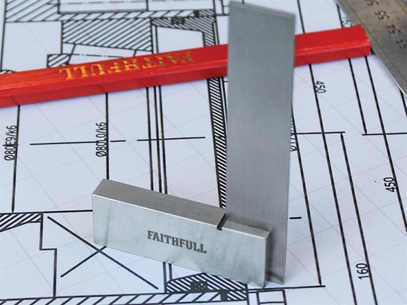 A metal engineers square labeled FAITHFULL stands on a technical drawing, with a red carpenter pencil and part of a steel ruler nearby. The drawing features architectural measurements and lines.