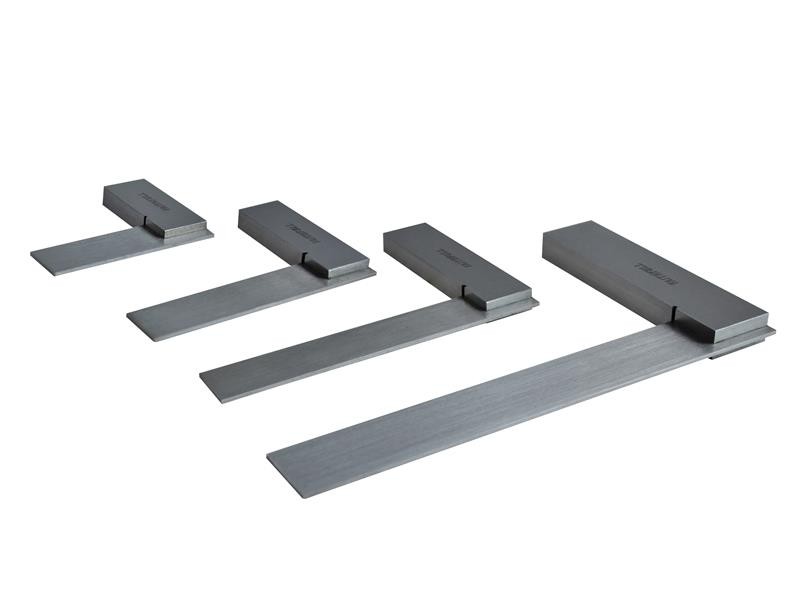 Four metal try squares of varying sizes are arranged diagonally on a white background, each with a thick rectangular handle and a flat, straight blade used for measuring and marking right angles.