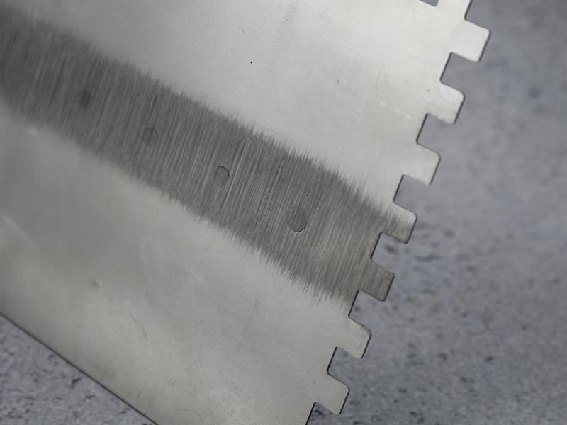 A Faithfull notched tile trowel with 115mm notches for combing adhesive on floors and walls, ensuring even coverage beneath tiles.