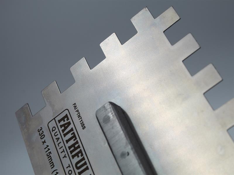 A Faithfull notched tile trowel with 115mm notches for combing adhesive on floors and walls, ensuring even coverage beneath tiles.