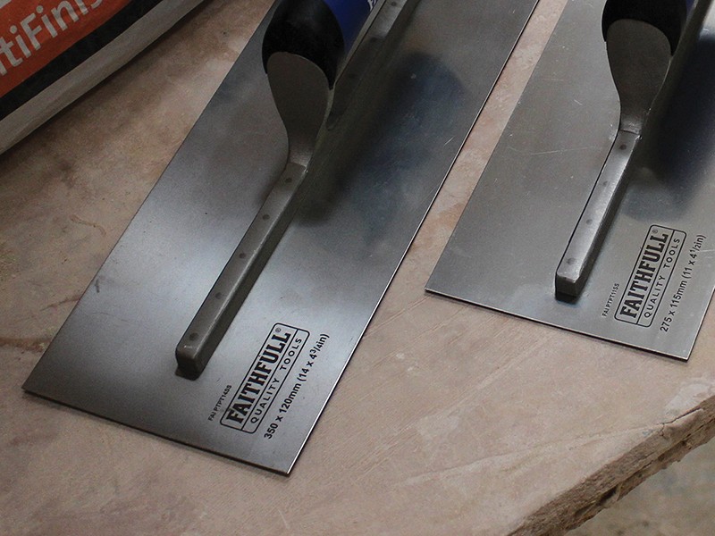 A Faithfull plasterer's finishing trowel with a thin, flexible steel blade and a turned wooden handle, for achieving smooth plaster surfaces.
