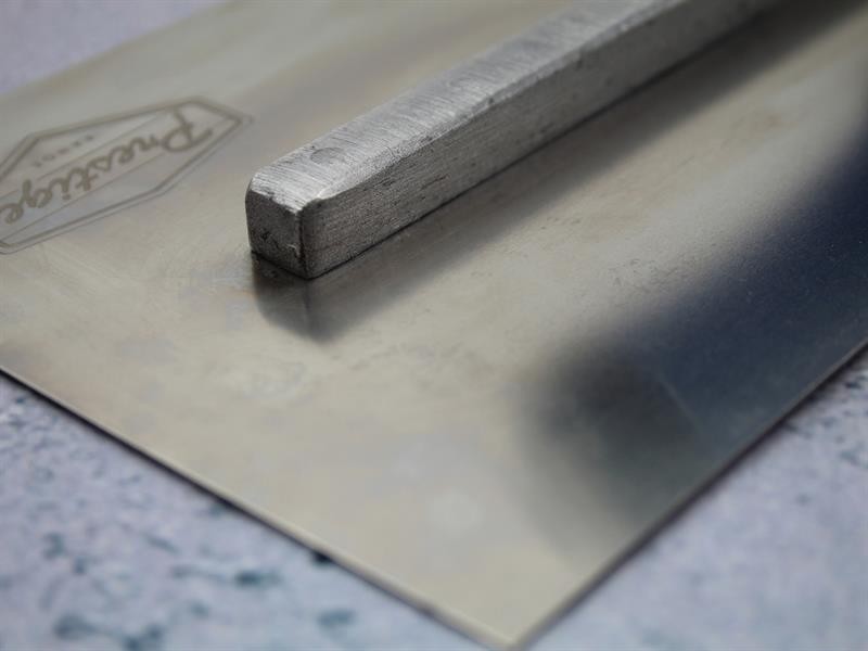 A Faithfull plasterer's finishing trowel with a thin, flexible steel blade and a turned wooden handle, for achieving smooth plaster surfaces.