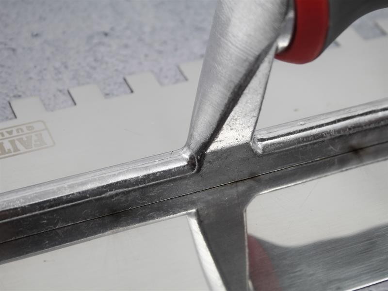 A Faithfull notched tile trowel with 10mm notches for combing adhesive on floors and walls, ensuring even coverage beneath tiles.