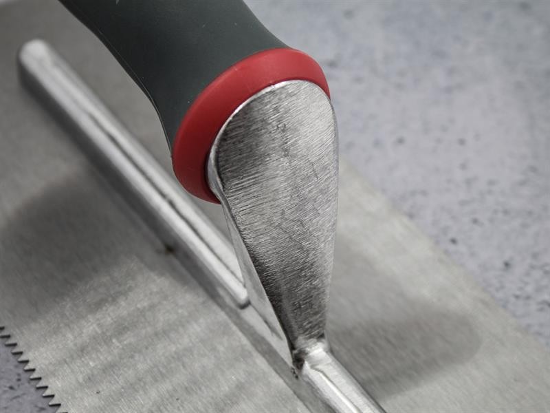 A Faithfull notched tile trowel with 3mm notches for combing adhesive on floors and walls, ensuring even coverage beneath tiles.