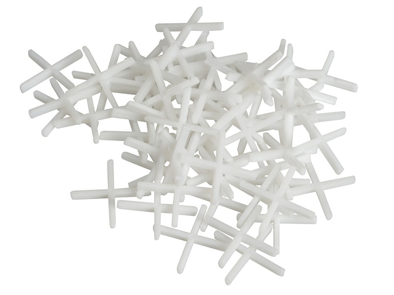 A pile of white plastic tile spacers arranged in a random heap on a white background.,
