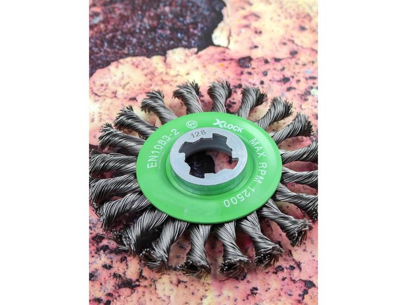 A wire brush with steel or brass bristle rows in a wooden or plastic handle, for removing rust, scale, and surface contaminants from metal.