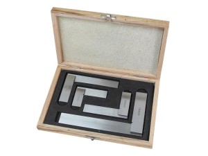 A wooden box with foam padding containing a set of metal engineers squares of various sizes, arranged neatly inside the box.