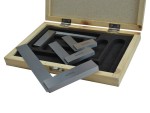A wooden box with foam padding holds several precision engineering squares made of metal, with some placed inside the box and others resting on top. The box lid is open, revealing its contents.