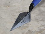 A Faithfull pointing trowel with a small triangular steel blade and a turned wooden or plastic handle, for filling and pointing mortar joints.