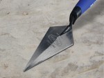 A Faithfull pointing trowel with a small triangular steel blade and a turned wooden or plastic handle, for filling and pointing mortar joints.