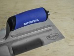 A Faithfull notched tile trowel with 115mm notches for combing adhesive on floors and walls, ensuring even coverage beneath tiles.