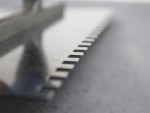 A Faithfull notched tile trowel with 115mm notches for combing adhesive on floors and walls, ensuring even coverage beneath tiles.