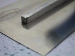 A Faithfull plasterer's finishing trowel with a thin, flexible steel blade and a turned wooden handle, for achieving smooth plaster surfaces.