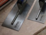 A Faithfull plasterer's finishing trowel with a thin, flexible steel blade and a turned wooden handle, for achieving smooth plaster surfaces.