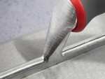 Close-up of a metal trowel with a red and gray handle on a smooth gray surface, showing the tools texture and fine details.